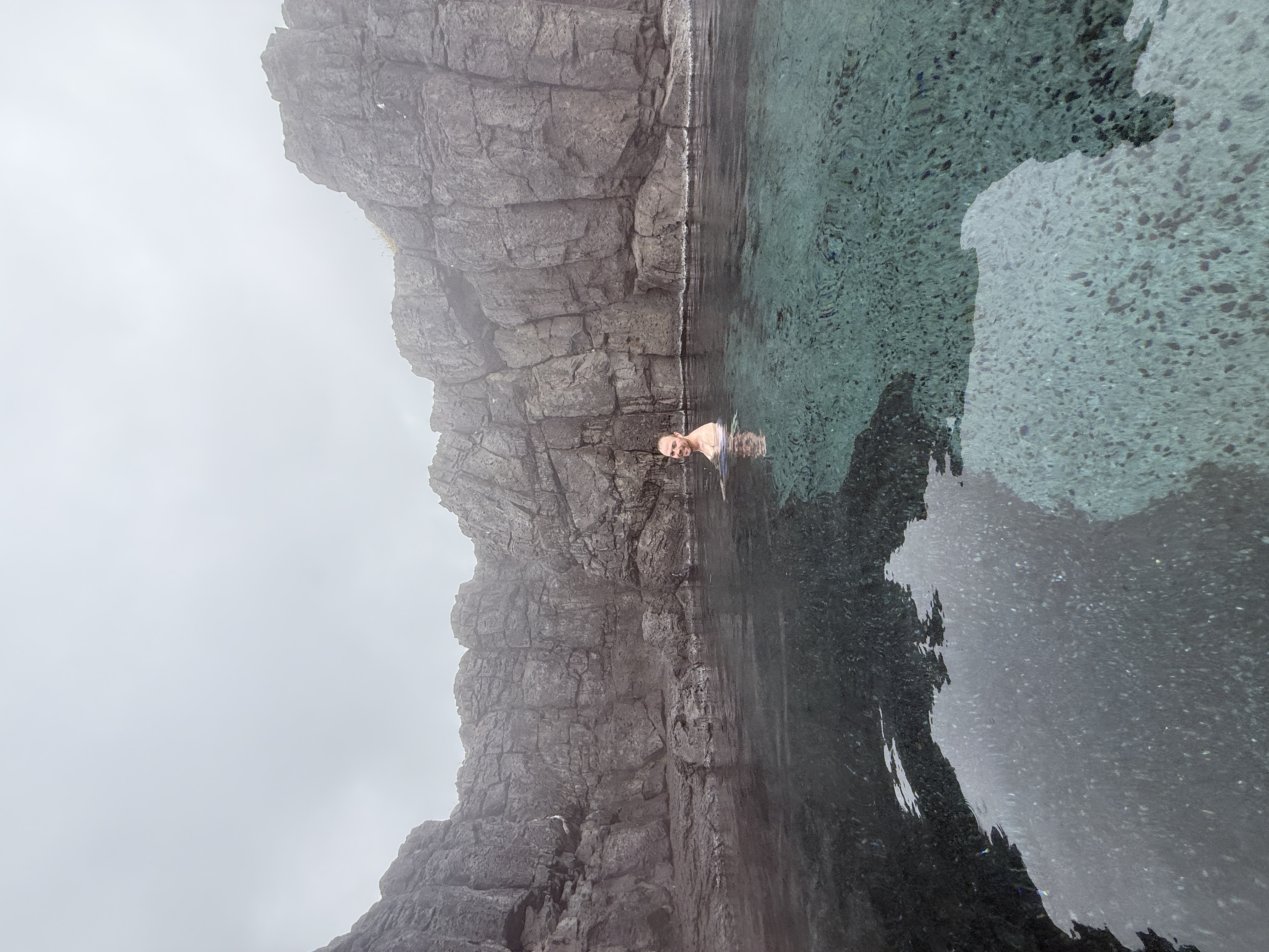 Andrew in a geothermal lagoon surrounded by dark rock